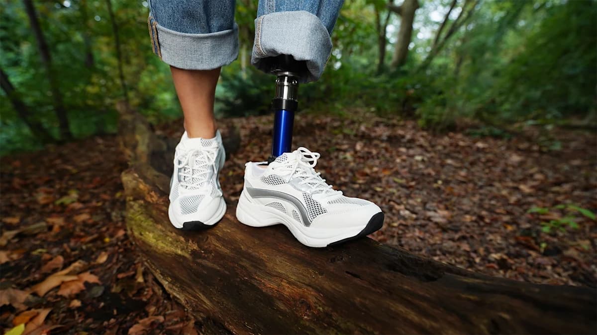 A woman wearing the Evanto prosthetic foot walking along a fallen tree trunk.