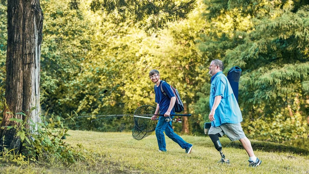 Accompanied by his son, a male user is walking up a hill with his Taleo prosthetic foot.