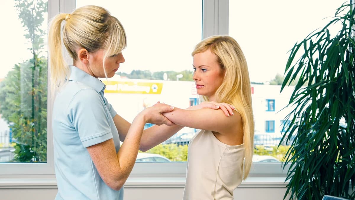 An orthotics and prosthetics professional examines an amputee's residual limb and arm movement