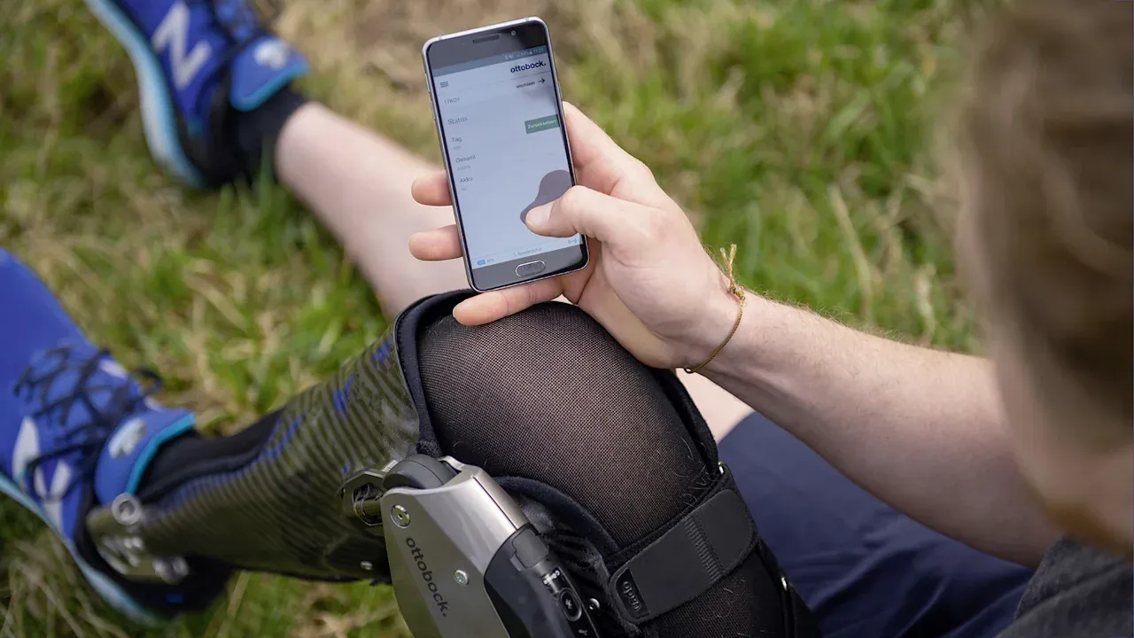 A C-Brace wearer uses their phone to access the Cockpit app to control their orthosis.