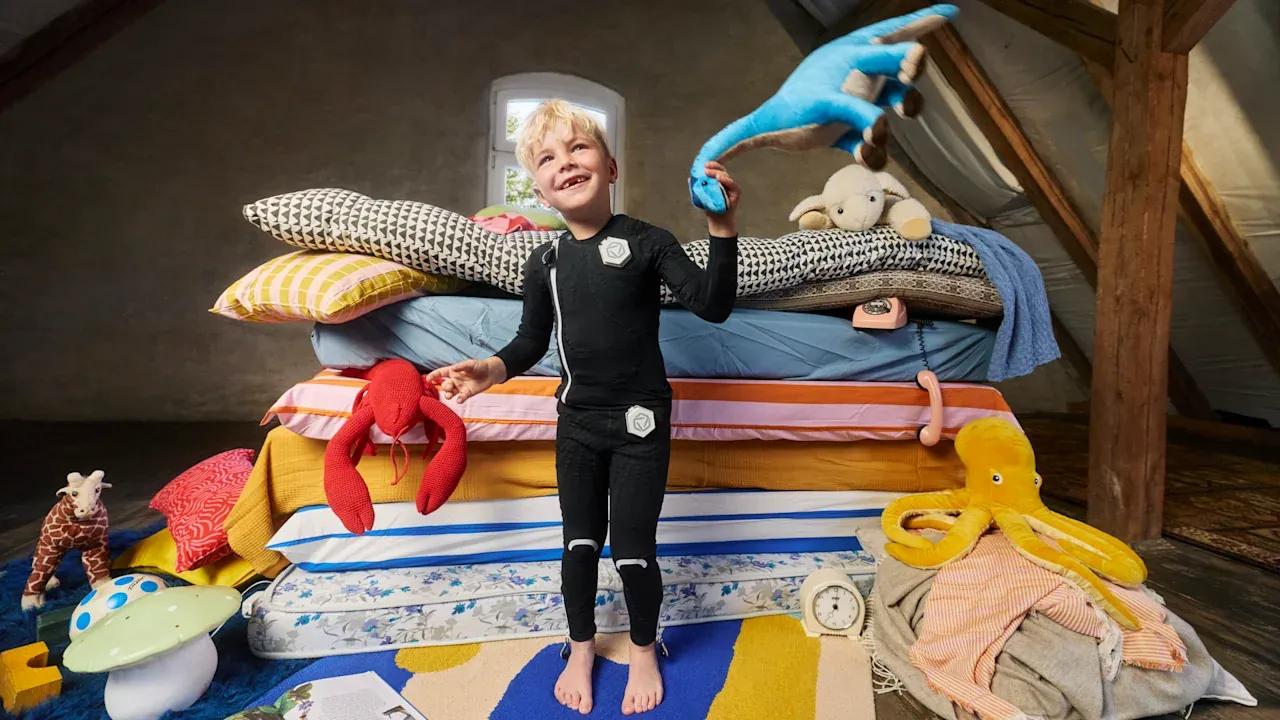 A child with cerebral palsy standing in front of his toys and colorful pillows.
