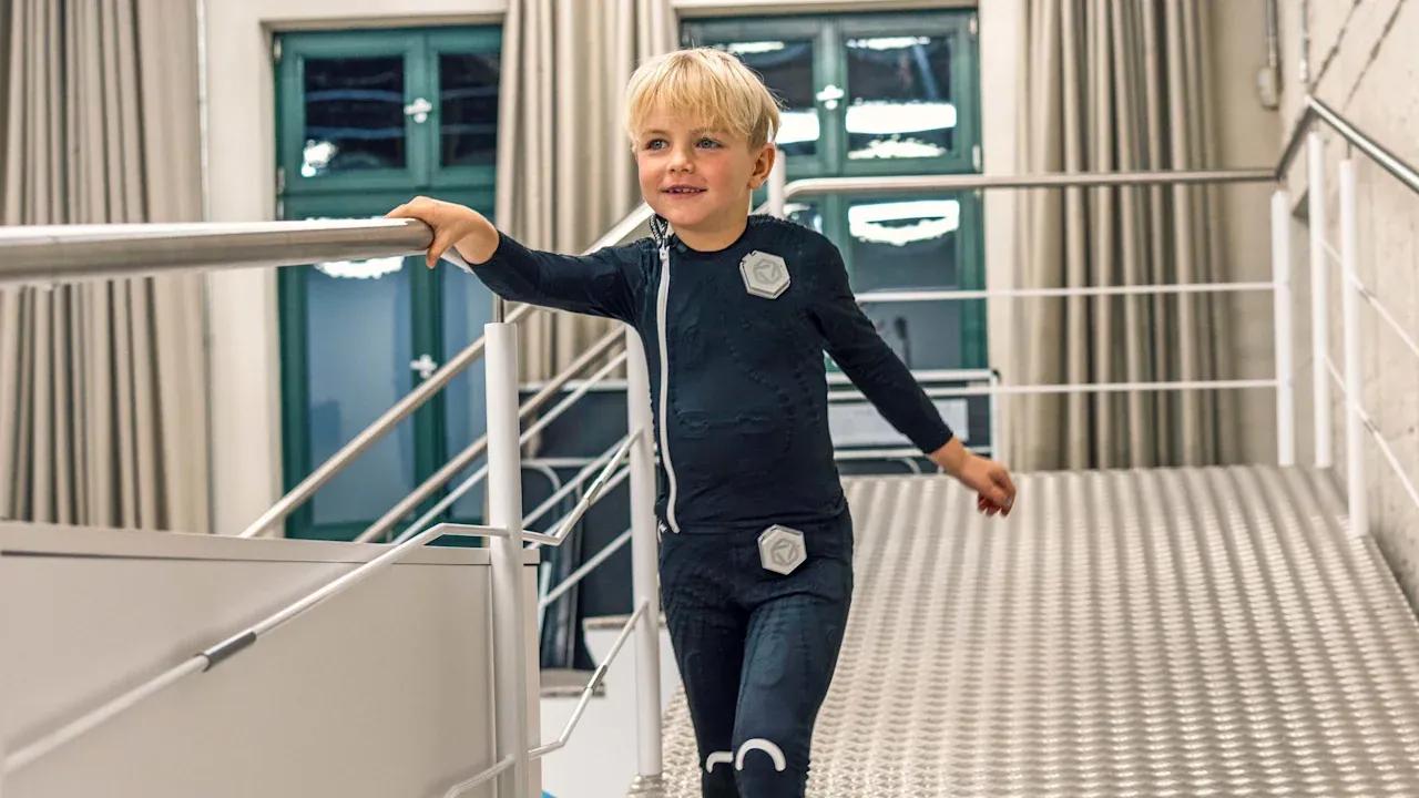 A child with cerebral palsy is walking while holding metal railings.