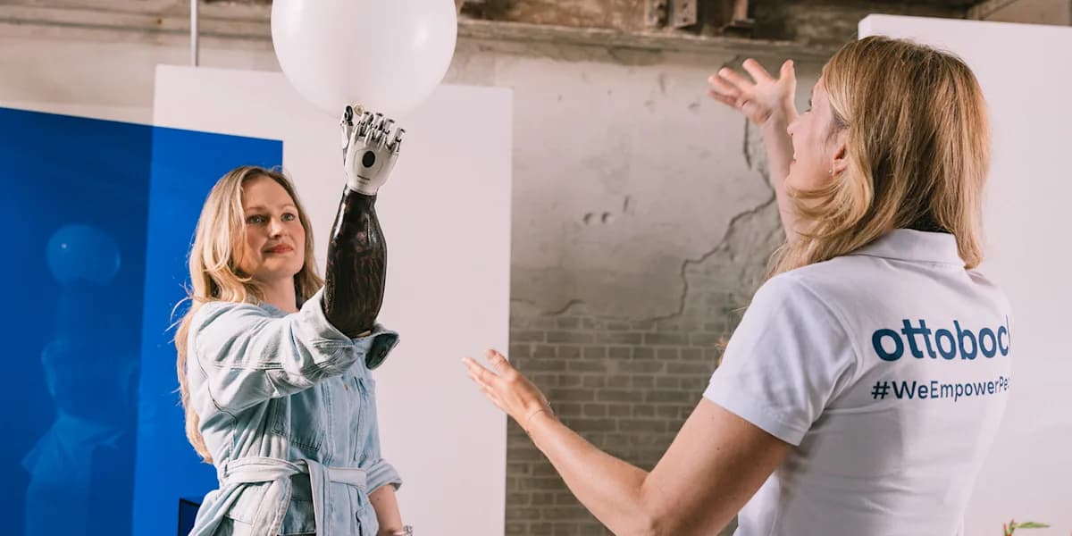 A bebionic user holding a white balloon with their prosthetic hand during a session with their physiotherapist.