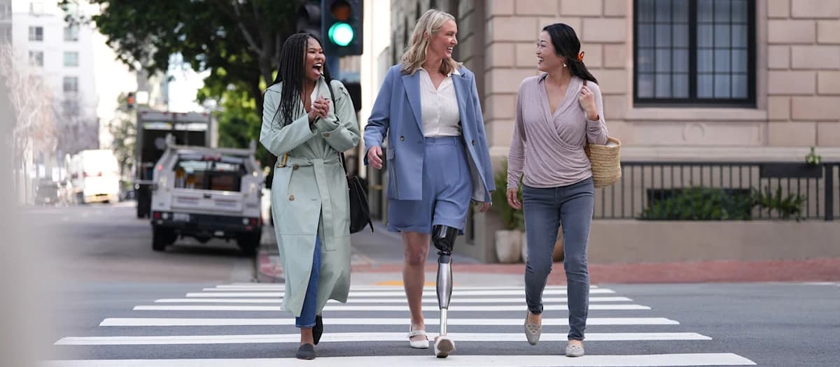 Three people crossing a pedestrian crossing, including one with a prosthetic leg.